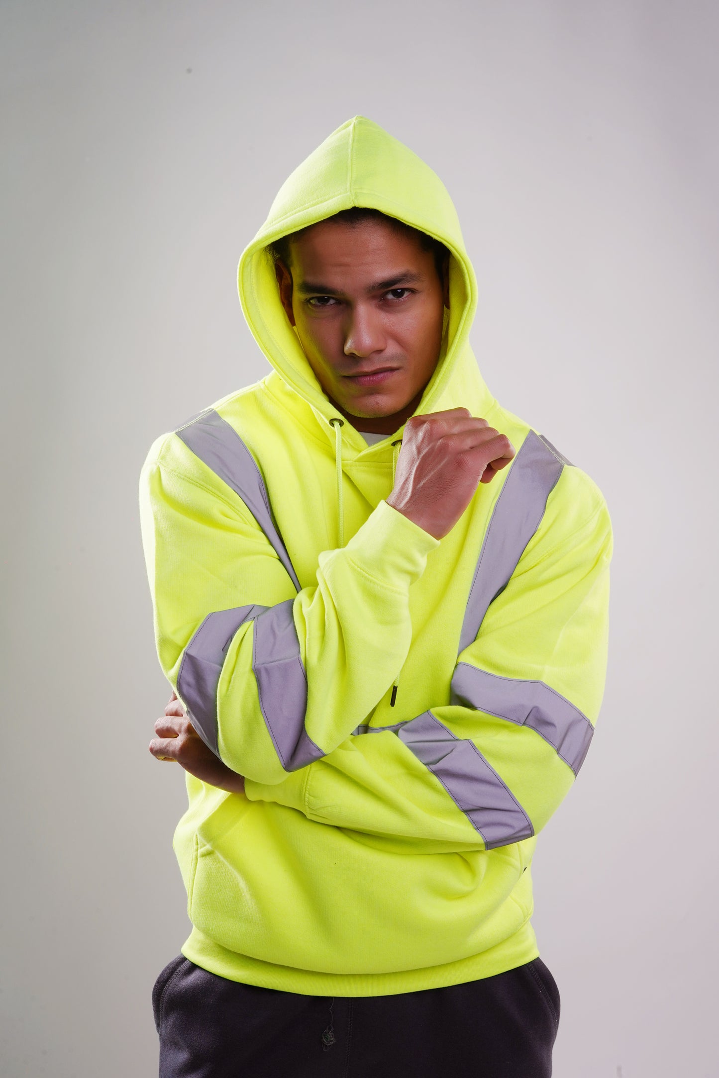 A person wearing a yellow safety hoodie with reflective silver stripes on the chest, shoulders, and sleeves.