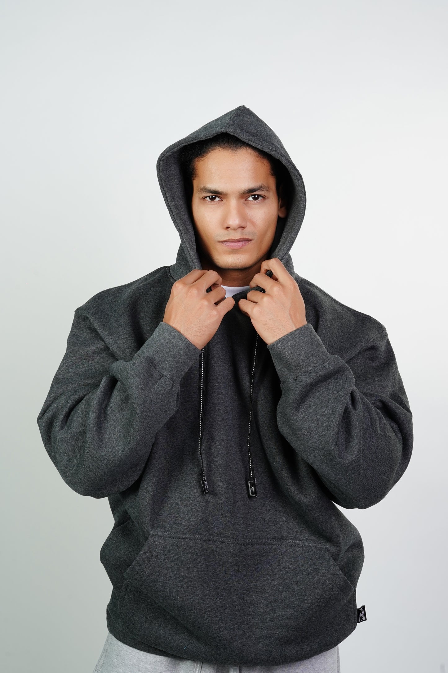 A person wearing a gray heavy fleece pullover hoodie with the hood up.