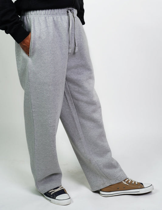 A person standing sideways, wearing gray open bottom jogger pants with a drawstring waist, and a black top. Feet are visible wearing brown shoes.