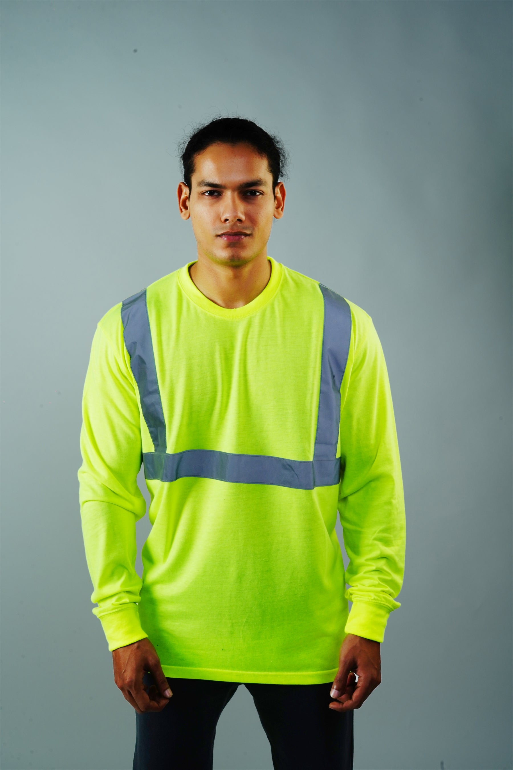 A person wearing a long sleeve yellow reflective tee-shirt with black reflective stripes on the shoulders.